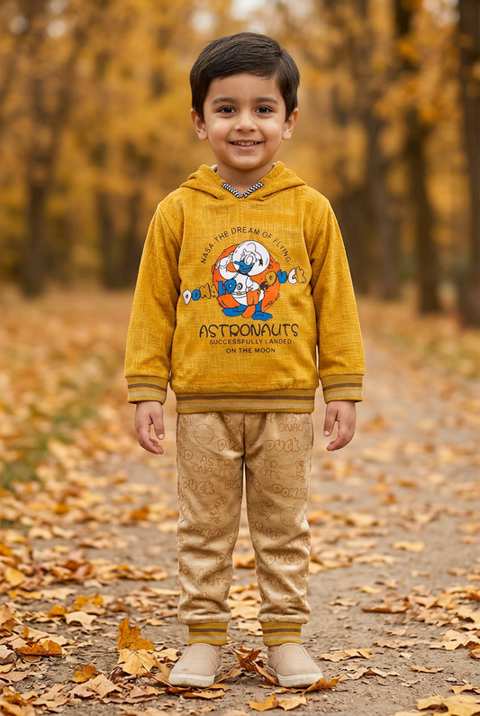 Child wearing BS809 mustard-yellow fleece hoodie with astronaut-duck artwork and beige printed joggers on an autumn park path.