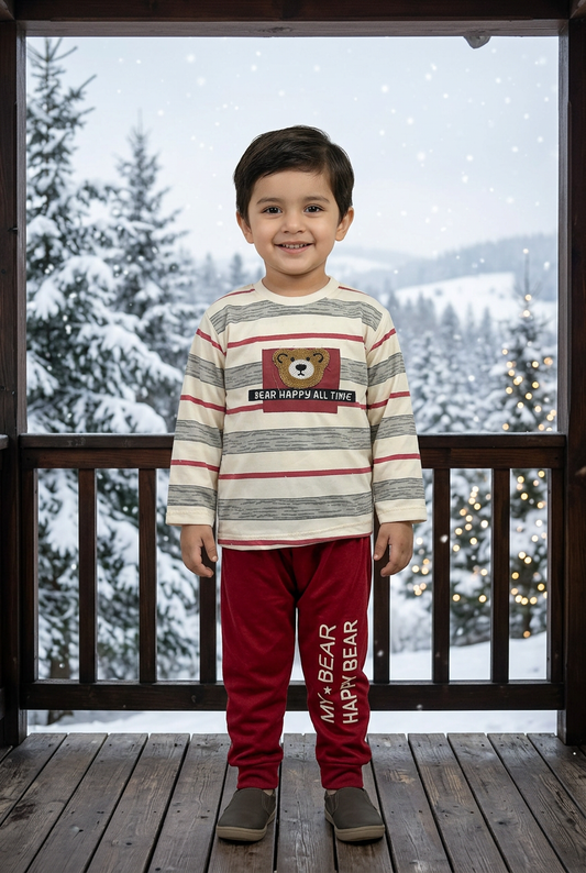 Child wearing BS786 cream striped bear-detail Terry sweatshirt and deep-red joggers on a chalet veranda overlooking snowy pines and soft lights