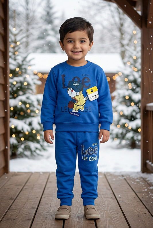 Child wearing BS782 royal-blue cartoon Terry sweatshirt with yellow-flap pouch detail and matching joggers on a veranda beside snowy pines and lights