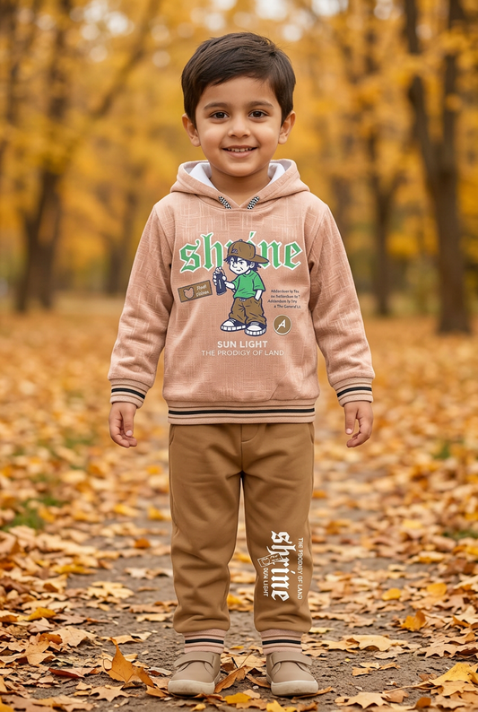Child wearing BS802 light-peach Shine graphic fleece hoodie and brown joggers with striped trims on an autumn park path.