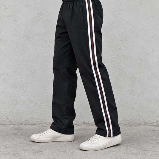 Man wearing black MT246 casual trousers with brown and white side stripes and off-white sneakers, cropped to legs and feet