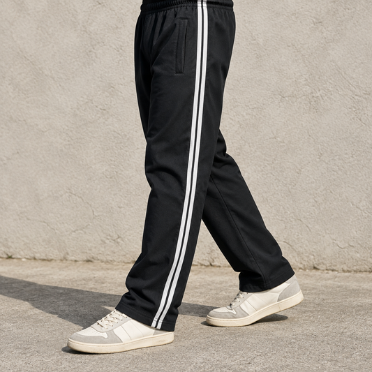 Man wearing black MT247 trousers with double white side stripes and retro sneakers, legs and feet only in natural daylight
