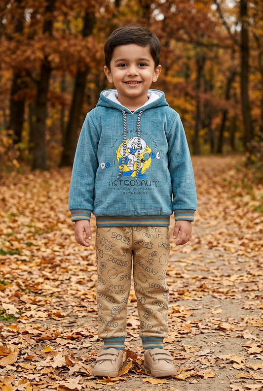 Child wearing BS808 teal-blue fleece hoodie with astronaut-duck artwork and beige printed joggers on an autumn park path.