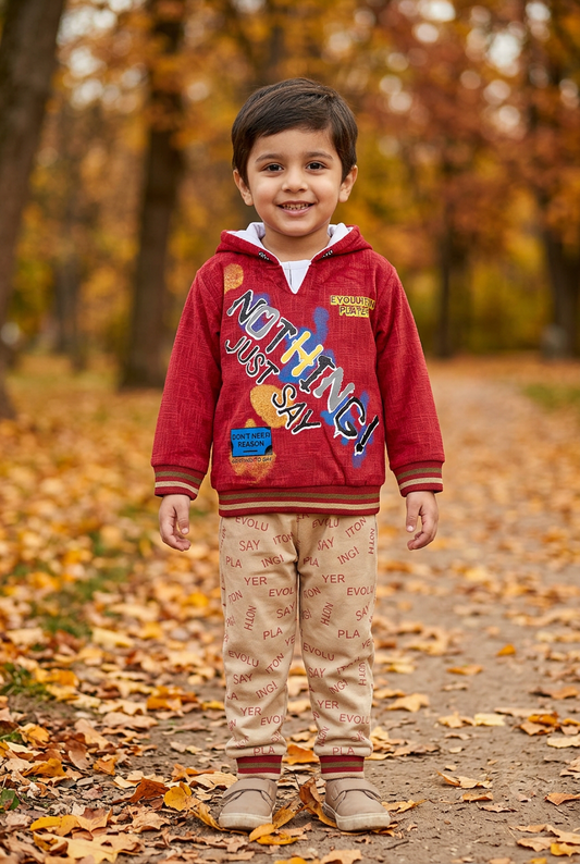 Child wearing BS806 red Nothing graphic fleece hoodie with striped trims and beige lettering-print joggers on an autumn park path.