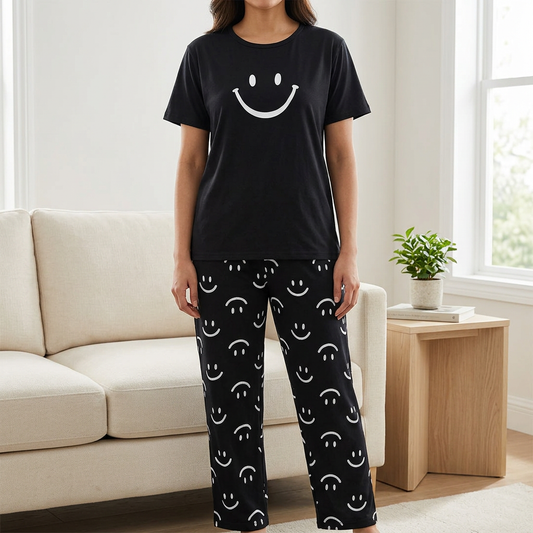Adult woman wearing WNS78 black smiley jersey tee and matching smiley-print trousers in a living room