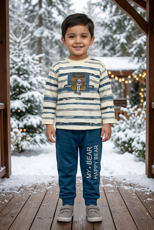 Child wearing BS789 cream brushstroke-striped Terry top with bear chest detail and blue joggers on a veranda overlooking snowy pines and soft lights