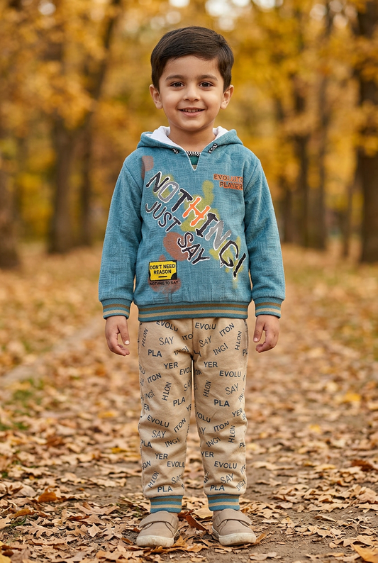 Child wearing BS805 teal-blue Nothing graphic fleece hoodie with striped trims and beige lettering-print joggers on an autumn park path.