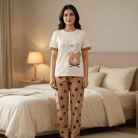 Adult Pakistani woman wearing WNS77 cream bear-print night suit top and tan matching trousers in a cozy bedroom.