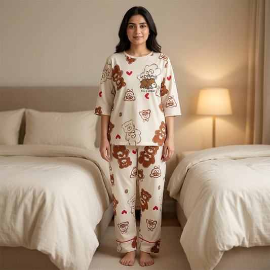 Adult Pakistani woman wearing the cream WNS76 night suit with brown bear and red heart prints in a cozy bedroom.