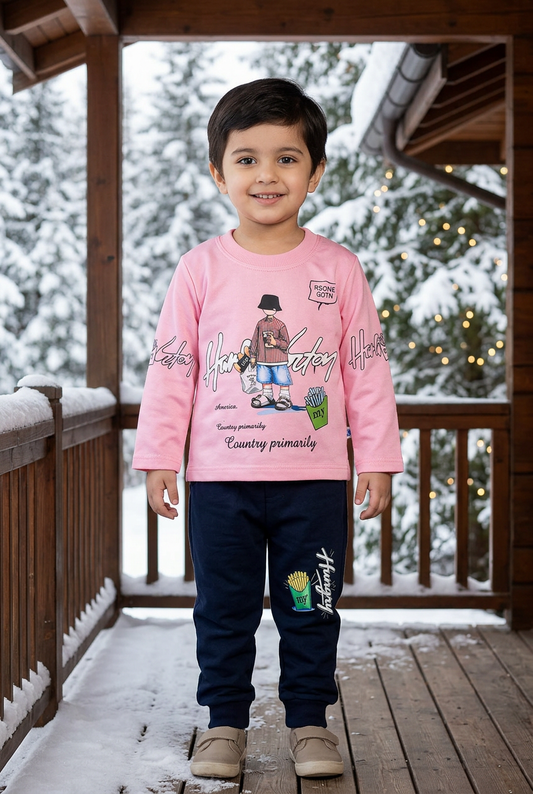 Child wearing BS834 light-pink character-print Terry top and navy fries-print joggers on a sheltered veranda with snowy pines and warm lights behind.